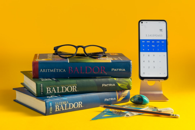 a stack of books and a cell phone on a yellow background — Foto por McCarthy Beckan na Unsplash