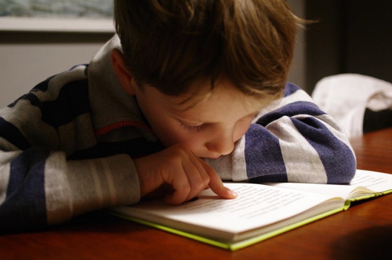 boy in gray and red hoodie reading book — Foto por Michał Parzuchowski na Unsplash