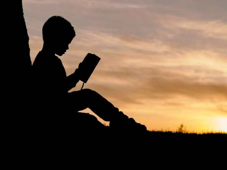 silhouette of child sitting behind tree during sunset — Foto por Aaron Burden na Unsplash