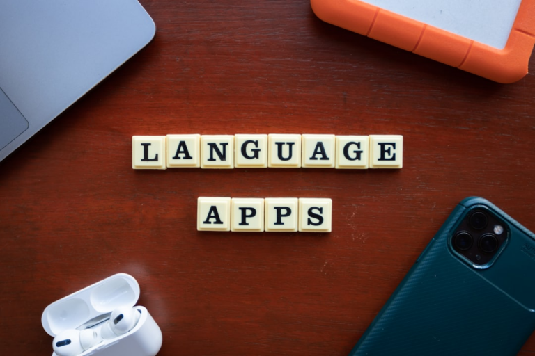 a wooden table topped with a cell phone and two scrabble tiles — Foto por Ling App na Unsplash