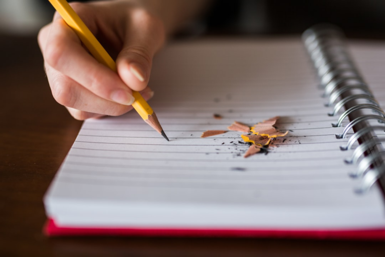 person holding pencil writing on notebook — Foto por Thought Catalog na Unsplash