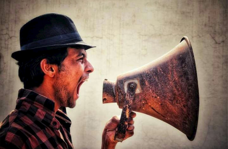 A man with a hat and a megaphone — Foto por Shubham Pawar na Unsplash